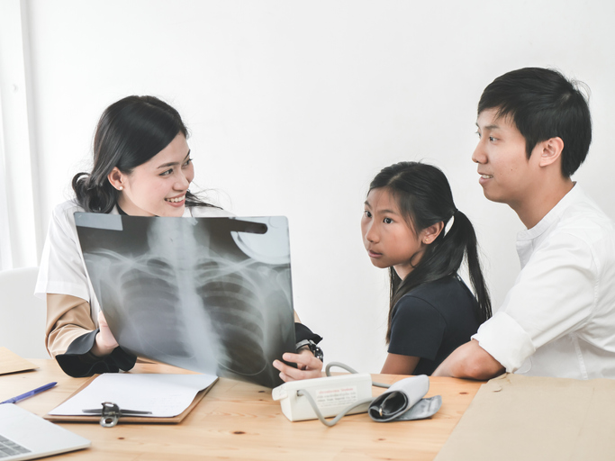 Asian doctor and child patient looking at xray film together.